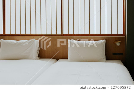 Minimalist Japanese hotel room with twin beds and soft white bedding, shoji screen. Modern ryokan interior Minimalist Japanese hotel room with twin beds and soft white bedding, shoji screen. Modern ryokan interior 127095872