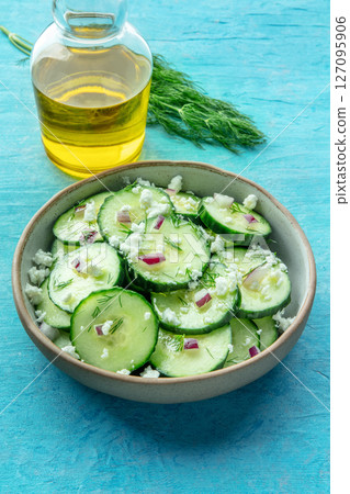 Cucumber salad with dill, red onion, and Feta cheese, on a blue background Cucumber salad with dill, red onion, and Feta cheese, on a blue background 127095906