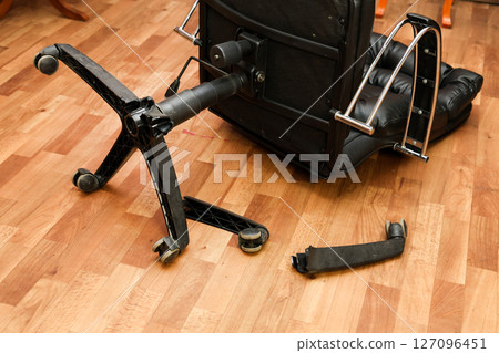 An office chair on the floor with broken legs: a symbol of poor workmanship and the need for repairs 127096451