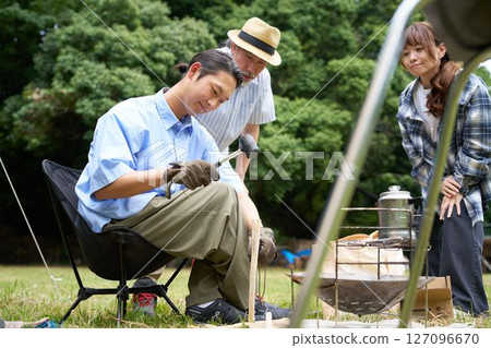 Young man splitting firewood with a hammer and knife Batoning image 127096670