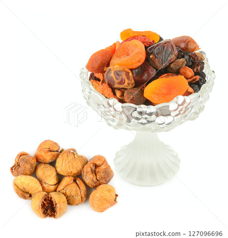 A selection of dried fruits in a vintage crystal fruit bowl and Figs isolated on white background. A selection of dried fruits in a vintage crystal fruit bowl and Figs isolated on white background. 127096696