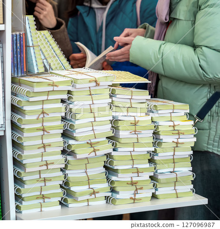 Young women and table with stack of books. Tall piles of various books stacked together in indoor store setting. Concept of books, literature abundance, choice overload and printed knowledge 127096987