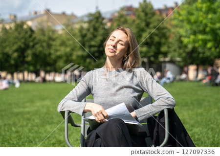 Happy relaxed woman soaking up sunny weathe in grassy park, taking time off from work in nature 127097336