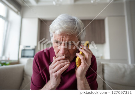 Suspicious elderly man with phone at home, targeted by scam artists, telemarketing fake news Suspicious elderly man with phone at home, targeted by scam artists, telemarketing fake news 127097351