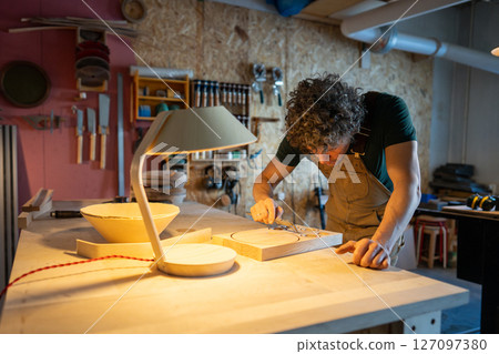 Woodworker using caliper to check upcoming lamp components, prepared patterns for bespoke furniture 127097380