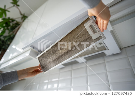 Dirty greasy oil exhaust filter held by homeowner, long overdue for cleaning. Health risks, bacteria 127097480