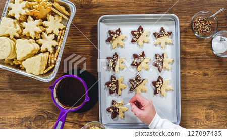 Flat lay. Creating snowflake-shaped cutout sugar cookies, dipped in chocolate, and adorned with different toppings. Flat lay. Creating snowflake-shaped cutout sugar cookies, dipped in chocolate, and adorned with different toppings. 127097485