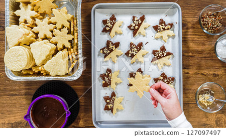 Flat lay. Creating snowflake-shaped cutout sugar cookies, dipped in chocolate, and adorned with different toppings. Flat lay. Creating snowflake-shaped cutout sugar cookies, dipped in chocolate, and adorned with different toppings. 127097497