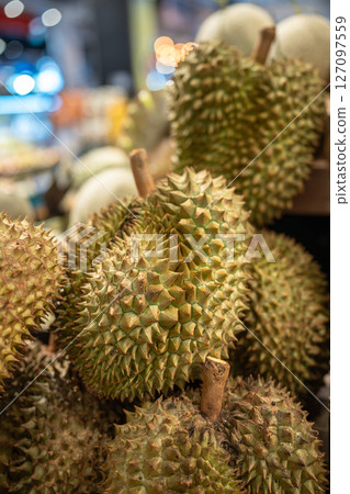 Durian fruits on supermarket shelf ready for customer selection, close up. Grocery stalls in Asia 127097559
