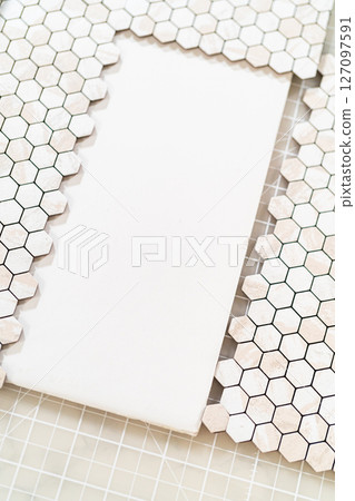 In the process of mounting peel and stick mosaic tiles onto a foam board, perfect for enhancing a food photography studio's aesthetic. 127097591