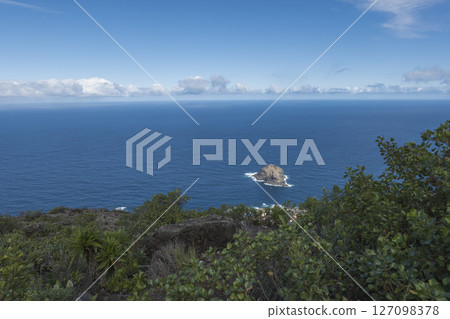 Aerial view of Roque de Garachico big rock in the ocean from Mirador de Garachico view point. Blue ocean with green vegetation. Popular tourist destination, Tenerife Canary Islands. Aerial view of Roque de Garachico big rock in the ocean from Mirador de Garachico view point. Blue ocean with green vegetation. Popular tourist destination, Tenerife Canary Islands. 127098378