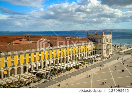 Wide shot of Commerce Square or Praca do Comercio in Lisbon, Portugal, iconic yellow Pombaline architecture, bustling outdoor cafes, Tagus River, city life, historic downtown, sunny day, sky with Wide shot of Commerce Square or Praca do Comercio in Lisbon, Portugal, iconic yellow Pombaline architecture, bustling outdoor cafes, Tagus River, city life, historic downtown, sunny day, sky with 127098425