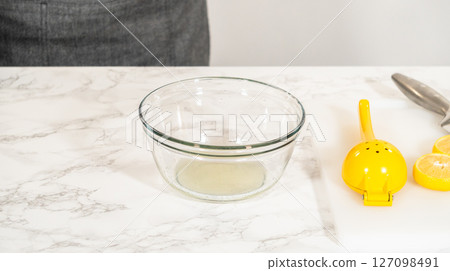 A lemon placed on a cutting board with a knife and lemon zest tool beside it, ready for zesting. This step is essential for adding fresh lemon flavor to the cookies. 127098491