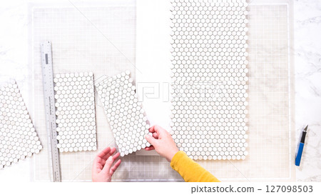 Flat lay. In the process of mounting peel and stick mosaic tiles onto a foam board, perfect for enhancing a food photography studio's aesthetic. 127098503