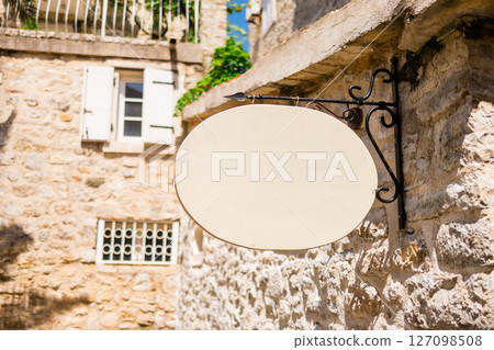 Blank signboard on stone building wall in Mediterranean alley. Concept of urban signage, empty brand space, and local European architecture. Copy space 127098508