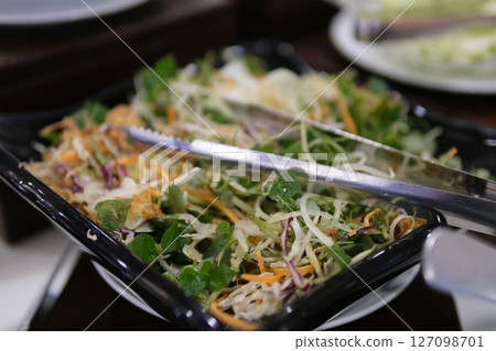 Salad vegetables serving Close up of man selecting food from a buffet counter filled with fresh salads, vegetables, and dishes at a self-service restaurant. Food choices on breakfast in hotel Salad vegetables serving Close up of man selecting food from a buffet counter filled with fresh salads, vegetables, and dishes at a self-service restaurant. Food choices on breakfast in hotel 127098701