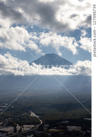 Mount Fuji emerges from drifting clouds with sun rays streaming down over Fujikawaguchiko Mount Fuji emerges from drifting clouds with sun rays streaming down over Fujikawaguchiko 127098739