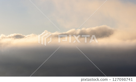 Layers of mist and clouds illuminated by the soft morning sunlight 127098741