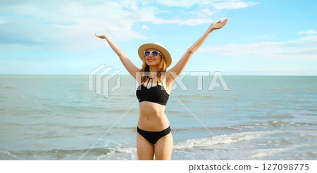 Summer vacation, beautiful happy woman in bikini swimsuit raising her hands up on the beach at sea 127098775