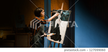 A girl is working on oil painting artwork in her workshop. 127099060
