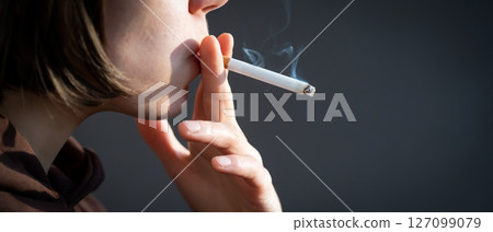 Woman is smoking, holding a cigarette in her hand. Woman is smoking, holding a cigarette in her hand. 127099079