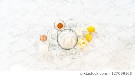 The image shows the ingredients for Lemon Spritz Cookies, including flour, sugar, butter, eggs, and fresh lemons, ready for baking. 127099168