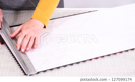 In the process of mounting peel and stick mosaic tiles onto a foam board, perfect for enhancing a food photography studio's aesthetic. 127099174