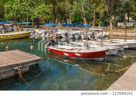 Colorful fishing boats moored in calm green water. Seaside lifestyle, coastal tourism, and peaceful harbor environment. Colorful fishing boats moored in calm green water. Seaside lifestyle, coastal tourism, and peaceful harbor environment. 127099191