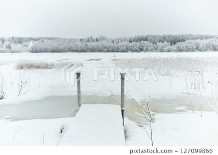 a frozen lake and a forest in frost around the lake, winter fairy tale in the forest, snow-covered tree branches, large flakes of snow are slowly falling, nobody a frozen lake and a forest in frost around the lake, winter fairy tale in the forest, snow-covered tree branches, large flakes of snow are slowly falling, nobody 127099866