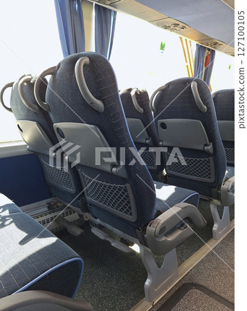 Empty bus interior with modern blue reclining seats and tray tables 127100105