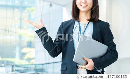 A smiling woman/businesswoman giving directions while holding a computer 127100185