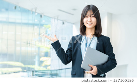 A smiling woman/businesswoman giving directions while holding a computer A smiling woman/businesswoman giving directions while holding a computer 127100186