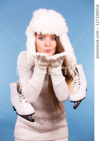 Woman wearing fur cap holding ice skates 127100658