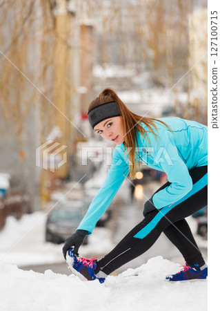 Winter workout. Girl wearing sportswear, stretching exercises. 127100715