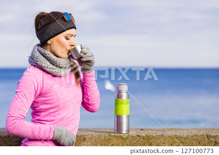 Fit woman in cold day warming up drink tea 127100773