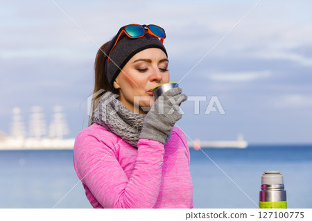 Fit woman in cold day warming up drink tea Fit woman in cold day warming up drink tea 127100775