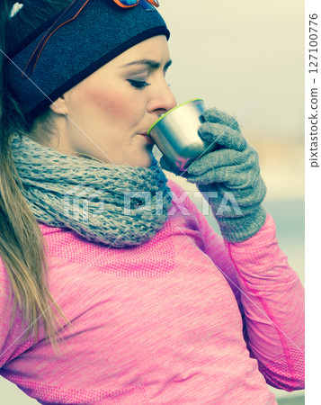 Fit woman in cold day warming up drink tea 127100776