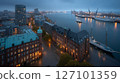 Stunning aerial view captures port during nighttime. City lights reflect on water, illuminating piers and vessels. Activity of shipping and commerce evident in the busy harbor. 127101359