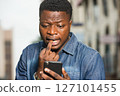 Close up of young african man with mobile phone. Close up of young african man with mobile phone. 127101455