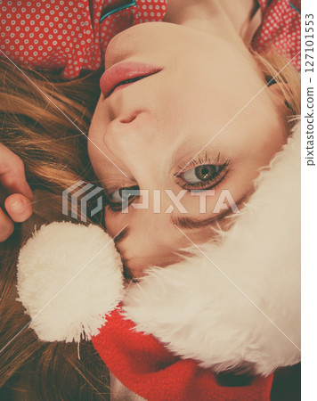 Happy woman wearing pajamas and Santa Claus hat 127101553