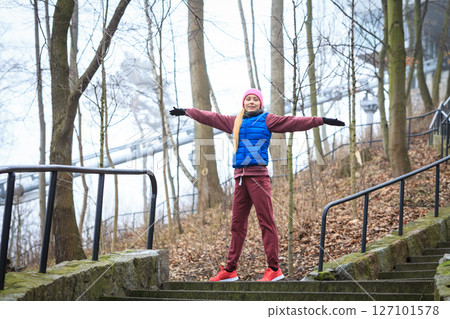 Woman wearing sportswear exercising outside during autumn 127101578