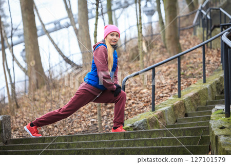 Woman wearing sportswear exercising outside during autumn 127101579