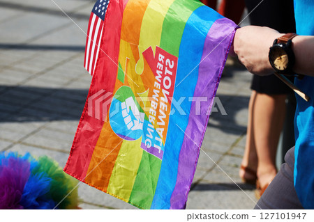Pride Celebration. Vibrant pride flag held with American flag during a sunny outdoor event. 127101947
