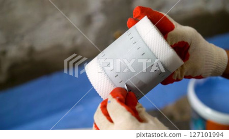 Construction worker installing waterproofing membrane on pipe Construction worker installing waterproofing membrane on pipe 127101994