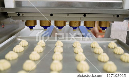 Industrial machine pouring cookie dough onto baking tray in food processing plant 127102015