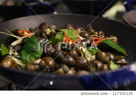 Grilled sea snails Person grilling sea snails on an outdoor grill 127102126