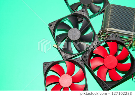 Computer fans, essential for cooling electronic components, are scattered on a green surface 127102288