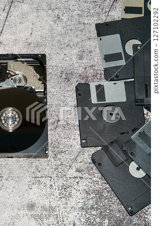 An open 3.5 inch hard drive next to several floppy disks on a grayish surface An open 3.5 inch hard drive next to several floppy disks on a grayish surface 127102292