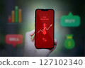 hand holding smartphone with financial charts 127102340