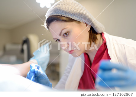 Gynecologist examines a patient laying on gynecological chair using medical vaginal speculum. Doctor takes pap smear test from a young woman cervix. Diagnosis of diseases. Woman reproductive health. Gynecologist examines a patient laying on gynecological chair using medical vaginal speculum. Doctor takes pap smear test from a young woman cervix. Diagnosis of diseases. Woman reproductive health. 127102807